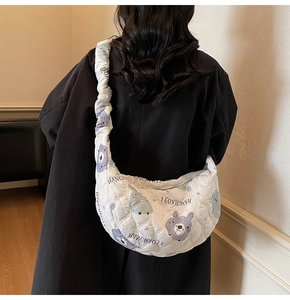 Dettaglio della borsa a mezzaluna trapuntata bianca con stampe cartoon e tracolla a pieghe