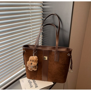 Detail view of brown faux suede tote bag with golden hardware and dog plush pendant