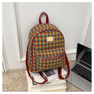 Détail d'un sac à dos vintage à carreaux avec bordure rouge et logo doré sur livres