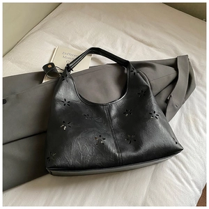 Détail du sac sous l'aisselle en similicuir noir avec texture plissée et motifs floraux découpés