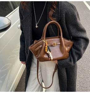 Detail of brown leather handbag with buckle straps and colorful beaded tassel accessory