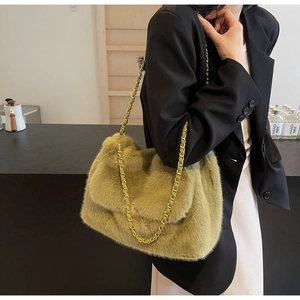 Détail d'un sac bandoulière en fausse fourrure verte avec chaîne dorée pour look d'hiver