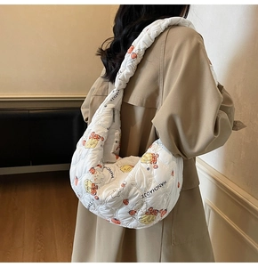 Dettaglio della borsa a mezzaluna bianca a pieghe con stampe cartoon indossata dal modello