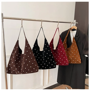 Detail of studded hobo bags in four colors hanging on a display rack with a blazer