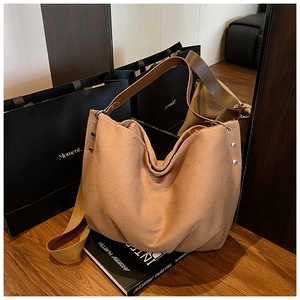 Close-up of caramel canvas tote bag showing silver rivets and dual texture straps