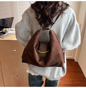 Detail view of suede backpack featuring leather flap and gold crescent buckle