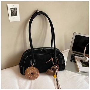 Detail of black suede underarm bag with contrast stitching and plush donut charm