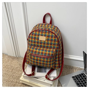Détail d'un sac à dos vintage en tweed à carreaux avec bordure en cuir rouge