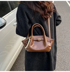 Brown vintage leather dumpling handbag with beaded charm and metal buckle detail