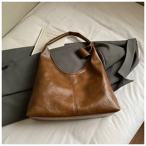 Détail du cabas marron vintage avec texture en cuir plissé sur fond minimaliste