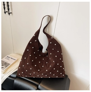 Close-up of a brown suede hobo bag featuring silver metallic stud details on a leather seat