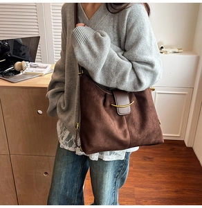 Detail of vintage brown suede tote bag with golden crescent buckle in a lifestyle setting