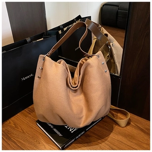 Detailed view of the large khaki tote bag with dark brown leather straps and metal rivets