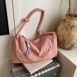 Detailed close-up of a pink quilted puff shoulder bag with decorative knotted shoulder strap