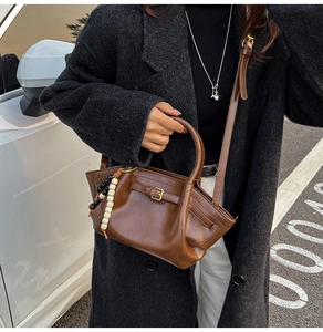 Outdoor street style shot of a dark brown leather handbag with a colorful bead charm