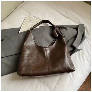 Détail du sac hobo en cuir PU marron café sur blazer gris avec bandoulière à nœud rétro
