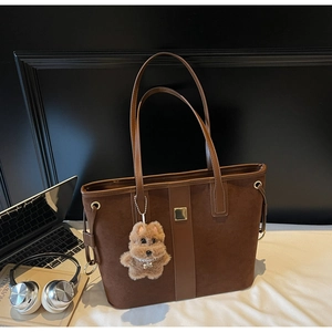 Deep brown suede tote bag featuring a cute plush dog pendant and modern workspace setup