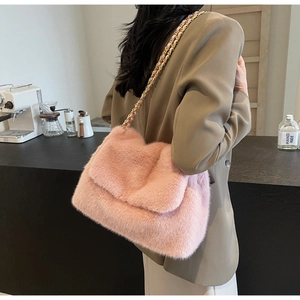 Détail du sac à bandoulière en peluche rose avec chaîne dorée porté par un mannequin