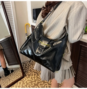 Detail of vintage black patent leather shoulder bag featuring a gold metallic buckle