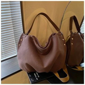Detail view of large dark brown canvas tote bag with side silver metal studs and leather strap