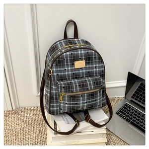 Détail d'un sac à dos à carreaux vintage avec imprimé étoile et plaque en métal doré
