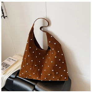 Detailed view of brown suede hobo bag with silver metallic studs on a black leather bench