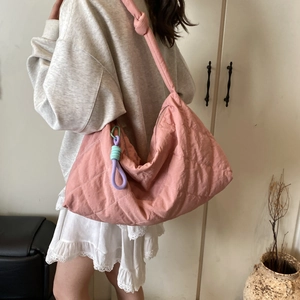 Pink quilted nylon hobo bag shown on shoulder featuring woven rope charm and knot detail
