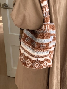 Sac seau en polaire sherpa à pois porté par un mannequin dans un cadre minimaliste