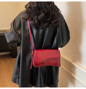 Detail of red patent leather shoulder bag with asymmetrical flap and glossy finish
