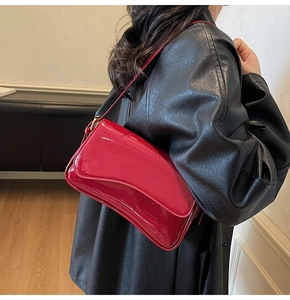 Detail of red patent leather shoulder bag with glossy finish and golden metal buckle