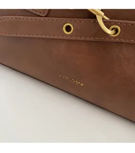 Detailed macro view of brown leather bag showing gold buckle and fine stitching details