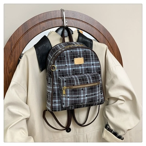 Détail d'un sac à dos vintage à carreaux avec plaque dorée et bretelles en cuir
