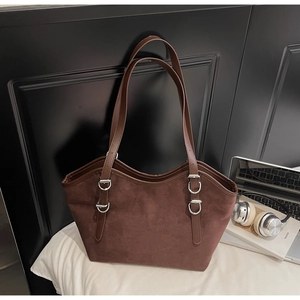 Dettaglio di una borsa tote retrò in pelle scamosciata marrone con fibbie argentate