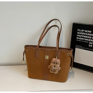 Detail of caramel suede tote bag with golden hardware and cute plush dog charm