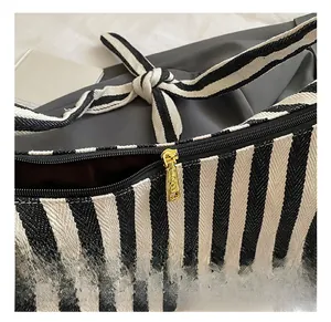 Détail macro de la fermeture éclair en métal doré et du patch logo en cuir sur sac en toile