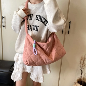Pink quilted hobo bag with colorful knot charm shown on model in a casual outfit