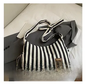 Détail du sac fourre-tout en toile à rayures noires et blanches avec écusson en cuir