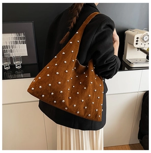Close-up of brown suede hobo bag with silver studs on minimalist coffee shop background