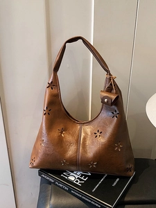 Sac cabas en cuir marron avec motifs floraux ajourés et mini pochette sur livre de mode