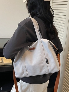 Large gray canvas tote bag with brown straps shown in a minimalist indoor lifestyle setting