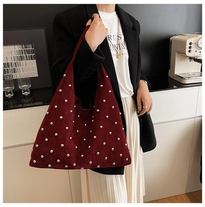 Model wearing a burgundy suede tote bag with silver studs in a minimalist setting