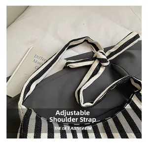 Gros plan sur la bandoulière tressée réglable avec nœud sur sac rayé noir et blanc