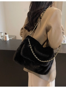 Sac à bandoulière en peluche noire avec chaîne dorée porté par un mannequin