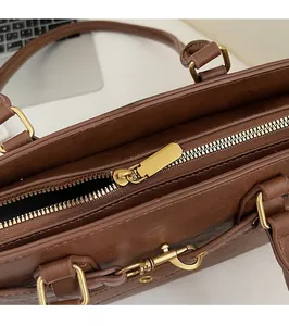 Detail of premium brown textured leather bag featuring a smooth gold metal zipper