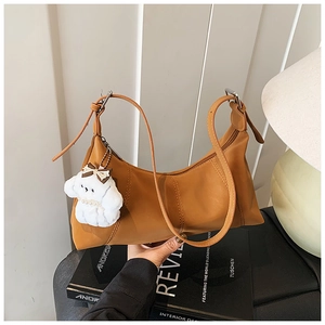 Detail of caramel faux leather shoulder bag with zipper and cute plush puppy charm