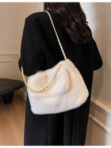 Sac bandoulière minimaliste en peluche blanche avec chaîne dorée porté par un modèle