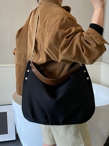 Large black canvas tote bag with brown leather handles and adjustable shoulder strap