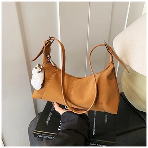 Detail of caramel faux leather dumpling bag with decorative stitching and plush charm