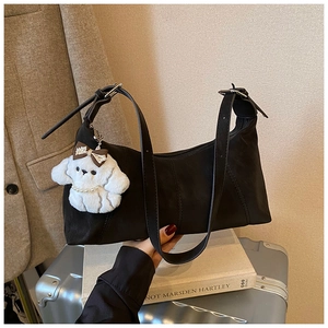 Detail of black dumpling bag with white plush puppy charm on stacked books
