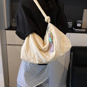 Quilted cream shoulder bag with creative cord pendant and stylish knotted strap detail